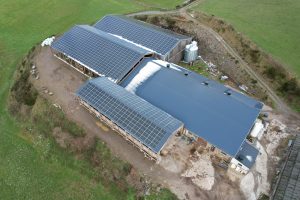 Vue aérienne de hangars agricoles équipés de panneaux solaires à Salles-Curan, illustrant des centrales photovoltaïques en toiture