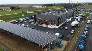 Vue aérienne par drone d’un site industriel équipé d’une centrale en autoconsommation photovoltaïque pour entreprise avec toiture solaire et ombrières de parking